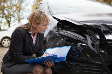 Female Loss Adjuster Writing Report On Damaged Car