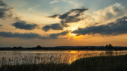 Sunset over the boats on the river. Yellow sun breaks through the clouds.