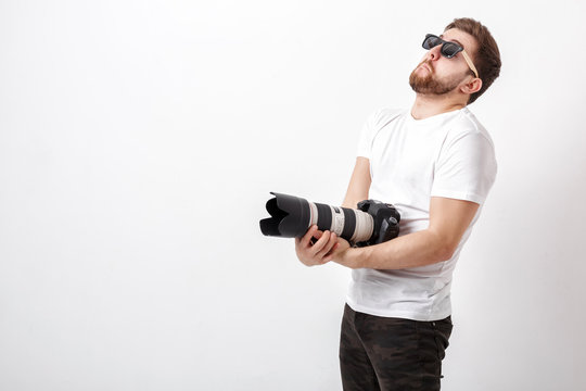 young professional photographer in shirt holds heavy digital cam