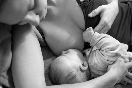 Mother breastfeeding a newborn baby boy BW