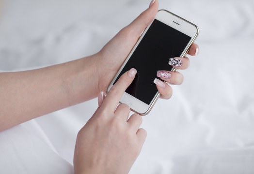 Closeup image of a teenager is searching information in network on mobile phone during free time. Young female student is revising photos on her cell telephone during break between lectures