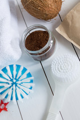 brown scrub into a glass jar towel cleaning brush, coconut craftsy paper on white wooden background