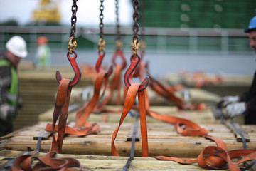 Chains and hooks hoist with slings for loading timber on board the vessel