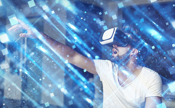 Young man with VR glasses playing virtual reality touching blue square polygons