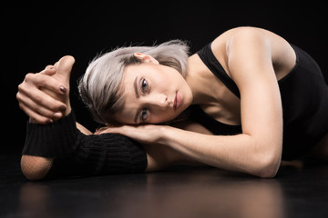 Fototapeta na wymiar Attractive sporty young woman dancer stretching and looking at camera