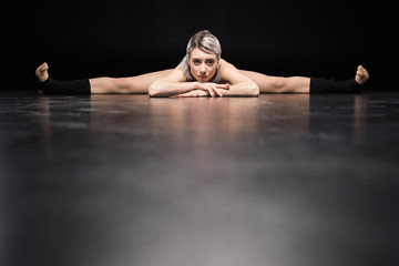 Fototapeta na wymiar Attractive young woman contemporary dancer stretching and looking at camera