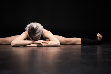 Sporty young woman dancer stretching on black