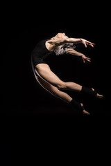 side view of jumping woman in bodysuit on black