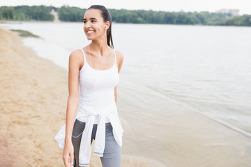 Fototapeta premium Athlete female fit girl runner jogging and running on beach lake in park. Woman jogging on sand training doing her cardio workout. Healthy lifestyle. Relax and looking away.