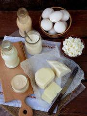 Set of fresh dairy products on wooden background: milk, cheese, cottage, yogurt, egg, mozzarella, ryazhenka, feta.