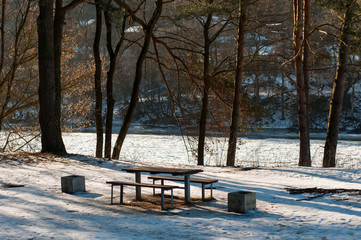 Bench and table in the forest near the river. Winter time.