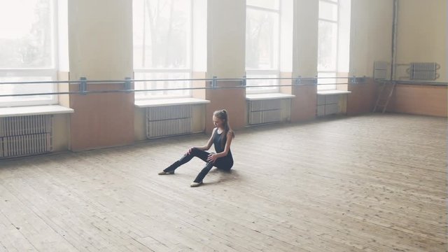 Elegant ballet dancer stretching in the lighted room