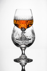 Crystal glasses with rum, carafe with whiskey on a glass table, white background