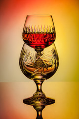 Crystal glasses with rum, carafe with whiskey on a glass table, colorful background