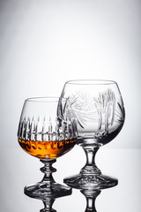 Crystal glasses with rum, carafe with whiskey on a glass table, white background