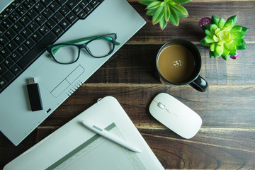 Top view of office stuff graphic design with pen mouse pad laptop wireless mouse and coffee cup on wooden table.Concept graphic design workplace.