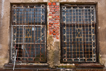 Broken windows shielded with metal grille. Tumbledown brick walls.