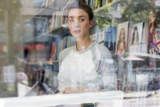 Young woman in a bookshop looking through window