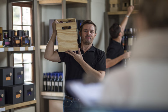 Man carrying crate of wine in shop