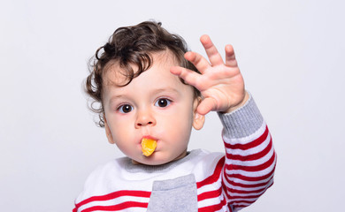 Portrait of a cute baby eating orange. One year old kid eating fruits by himself. Adorable curly hair boy being hungry biting on a slice of orange. - 138076841