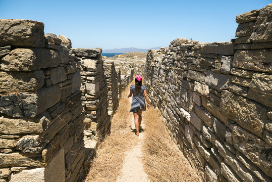 Greece, Mykonos, Delos, woman walking along the old houses at archaeological site