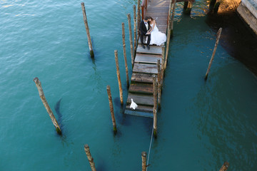 Fototapeta na wymiar Groom and bride on a deck near water