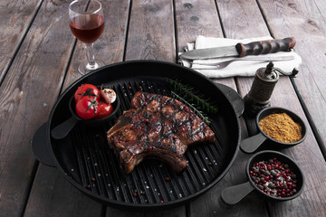 bone steak on a grill with vegetables on the table
