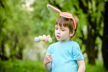 Little boy hunting for easter egg in spring garden on day. Cute child with traditional bunny celebrating feast