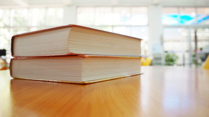 Book stack on wood desk in the library room with blurred focus for background, education back to school concept