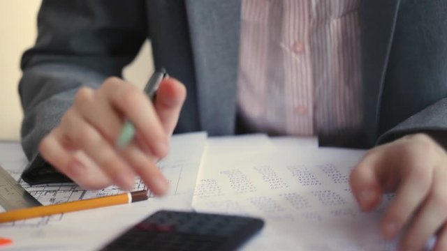 Architect with blueprint and calculator estimating project cost.