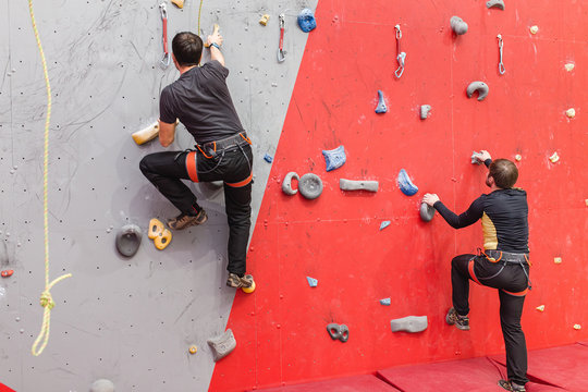 Two climbers compete in a friendly match in the climbing gym indoors