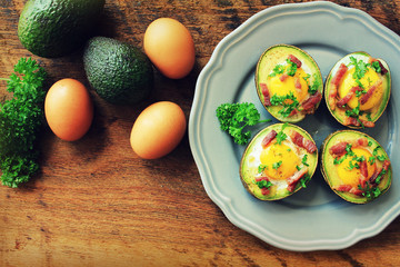 Avocado Egg Boats with bacon on wooden table. Top view.