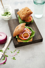 Vegan burger with quinoa cutlet, salad and vegetables. Gray shabby wooden background 
