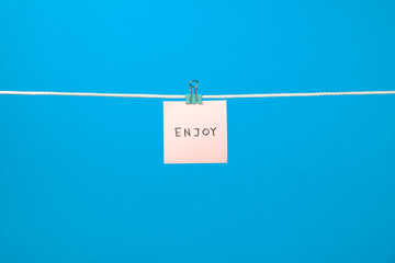 Pink paper note on clothesline with text Enjoy