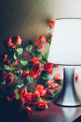 Artificial red flowers in bright light bulb. Artificial roses, beautiful composition.