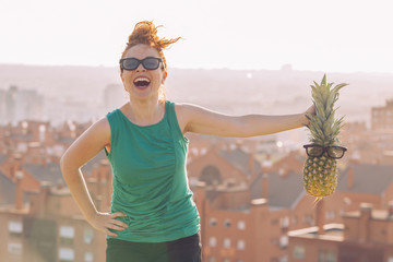 joyful young girl with glasses holding a pineapple