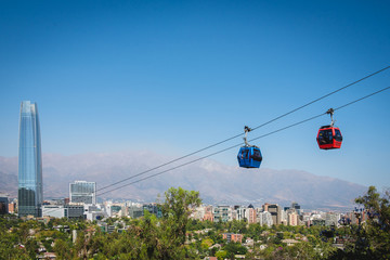 The cable way with different colored cabins on the background of Santiago, Chile.