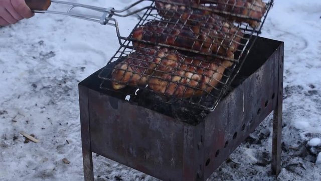 Man roasts barbecue on the grill in the winter and turns from one side to the other