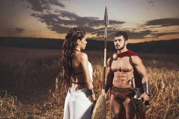 Woman like greece and man in armour meeting in field.