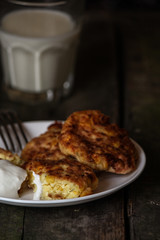 pancakes with cottage cheese and corn (cheesecakes) with a glass of milk on the table