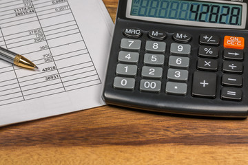 Calculator And Finance Document On Wooden Table
