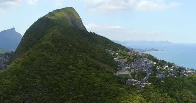 Aerial above the green mountain with favela on the hill, Rio de Janeiro, Brazil