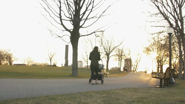 mother pushing stroller through park in fall