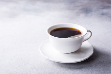 White cup of coffee with amaretti cookies on light gray background with copy space.
