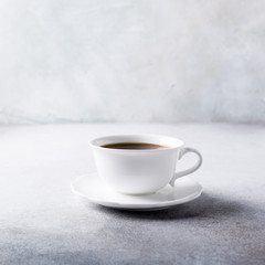 White cup of coffee with amaretti cookies on light gray background with copy space.