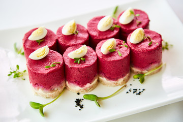 layered salad with herring, beets, carrots, onions, potatoes and eggs close-up on a plate....