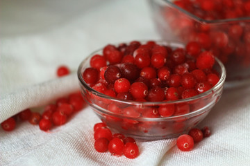 Berries cranberries glass plate in front of a white linen cloth, close-up, selective focus