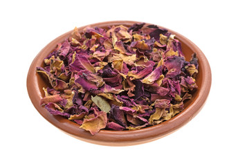 Dried crushed red rosebuds and petals in a small clay bowl isolated on a white background.