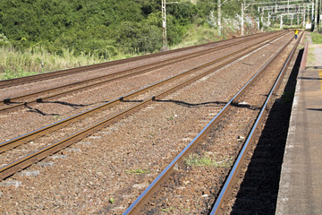 Obraz premium Twin Rail Tracks Leading Through Rural Railway Station