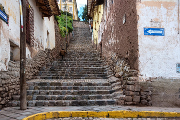 Fototapeta na wymiar Unidentified old man climbing tall set of cobblestone stairs in Cusco, Peru